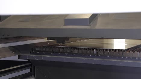 slow motion side view of laser cutting machine working on metal plate