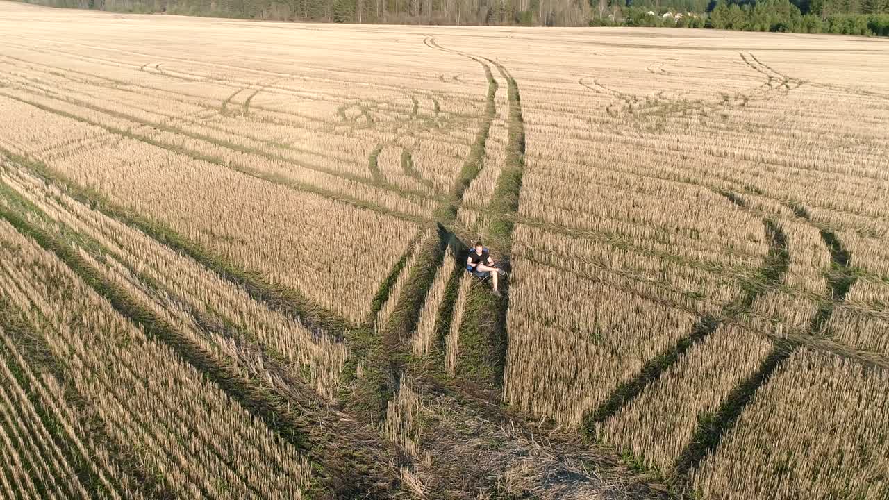hombre está descansando del trabajo. joven sentado en la silla en el campo y mirar el teléfono. vista panorámica aérea.