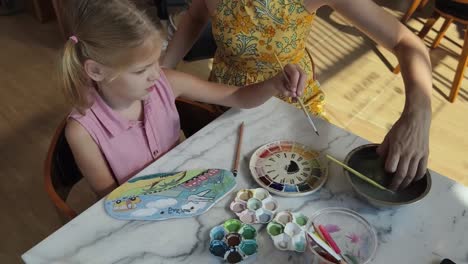 mother and daughter painting pottery together