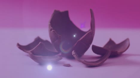Animation-of-light-over-broken-chocolate-egg-on-pink-background