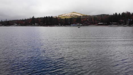 Beautiful-aerial-view-following-bird-flying-over-mountain-lake-on-a-stormy-day