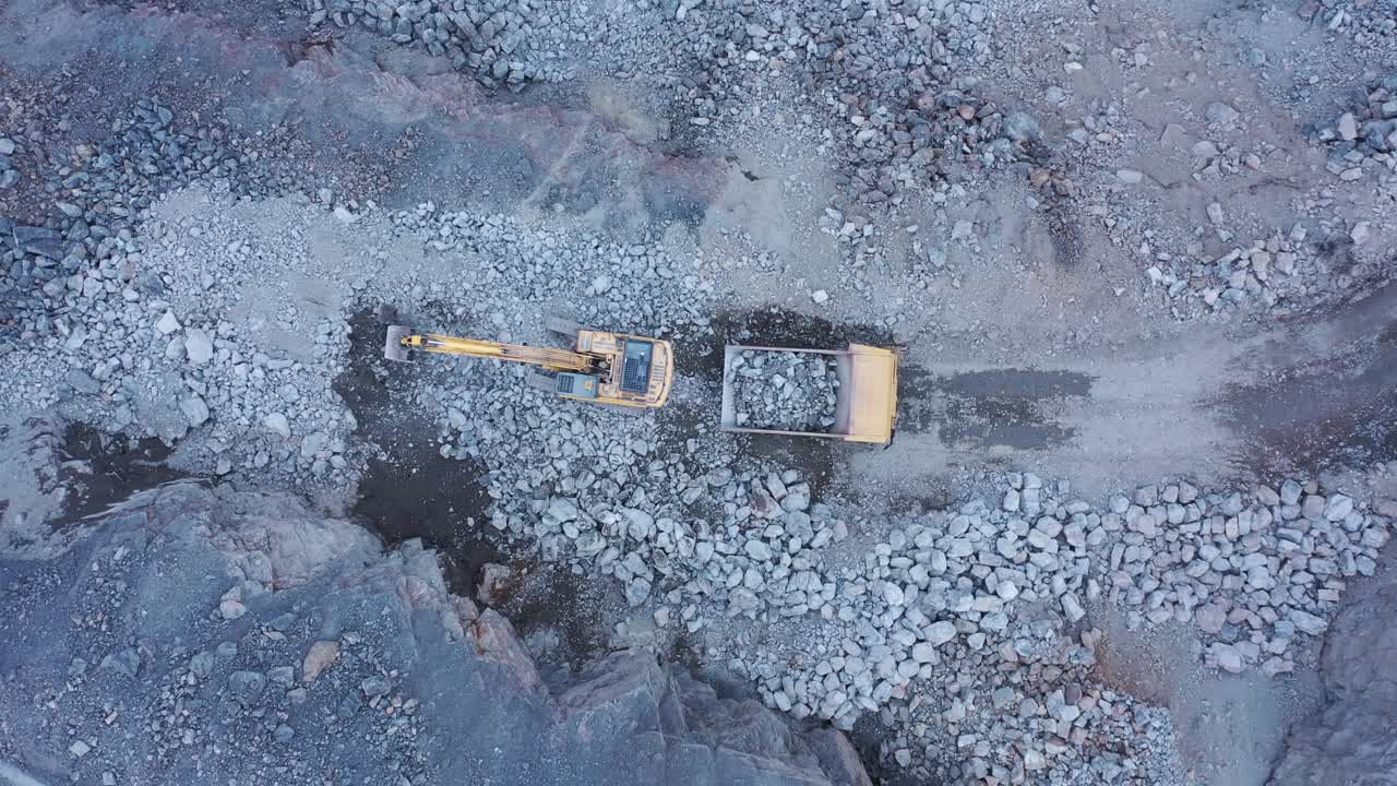 toma panorámica aérea de excavadora colocando rocas camión volquete