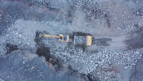 aerial panning shot of excavator placing rocks dump truck