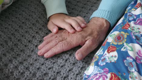la mano del niño acaricia la vieja mano arrugada de la anciana.
