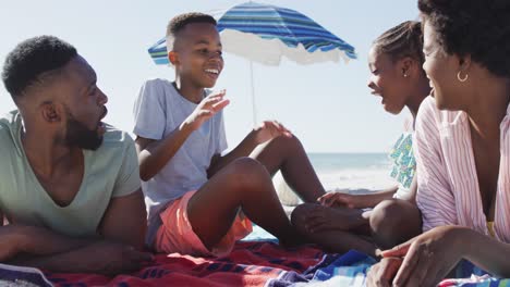 video of happy african american family lying on beach and laughing