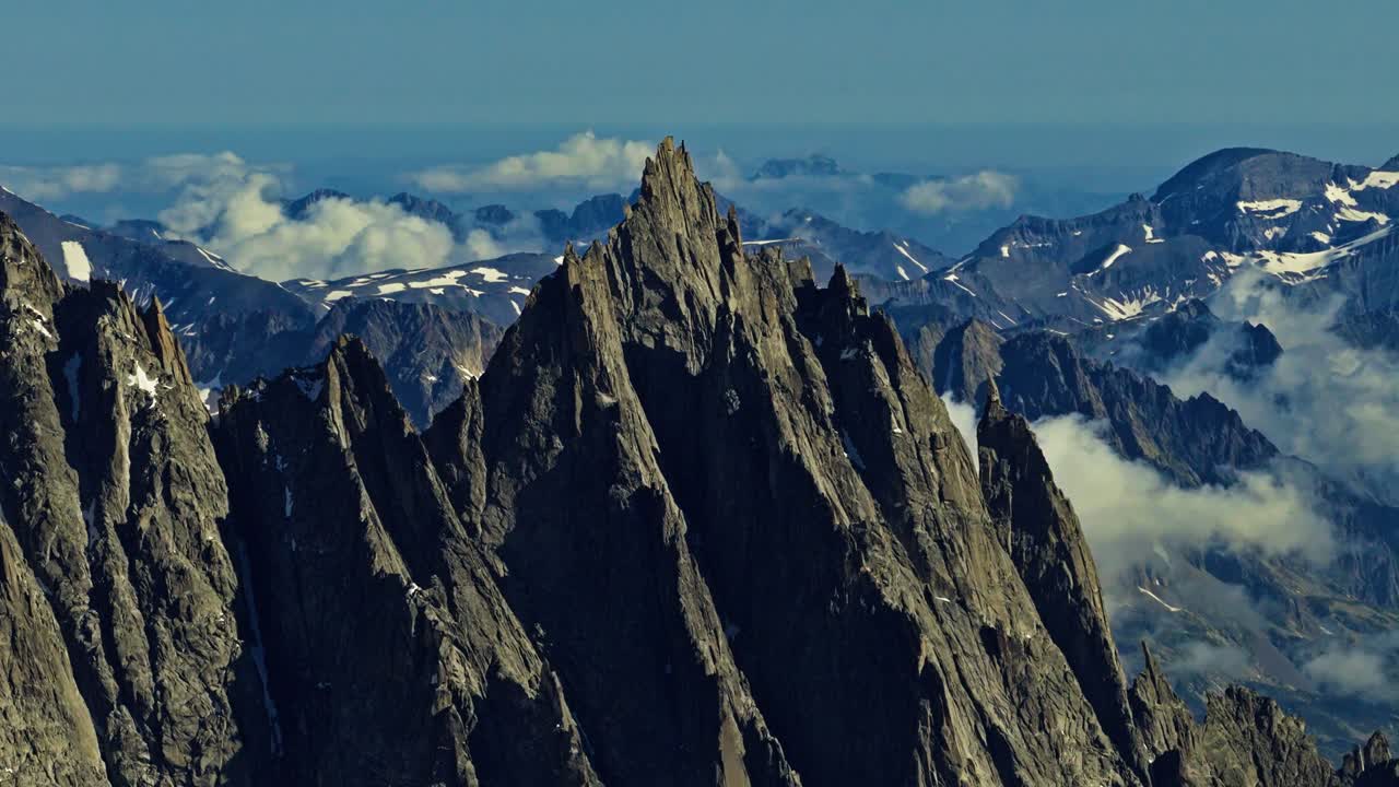 Vista aerea di un'aguzza vetta alpina frastagliata con terreno montano innevato e nuvole nella valle distante a Chamonix, Francia. Ideale per temi di viaggio e natura.