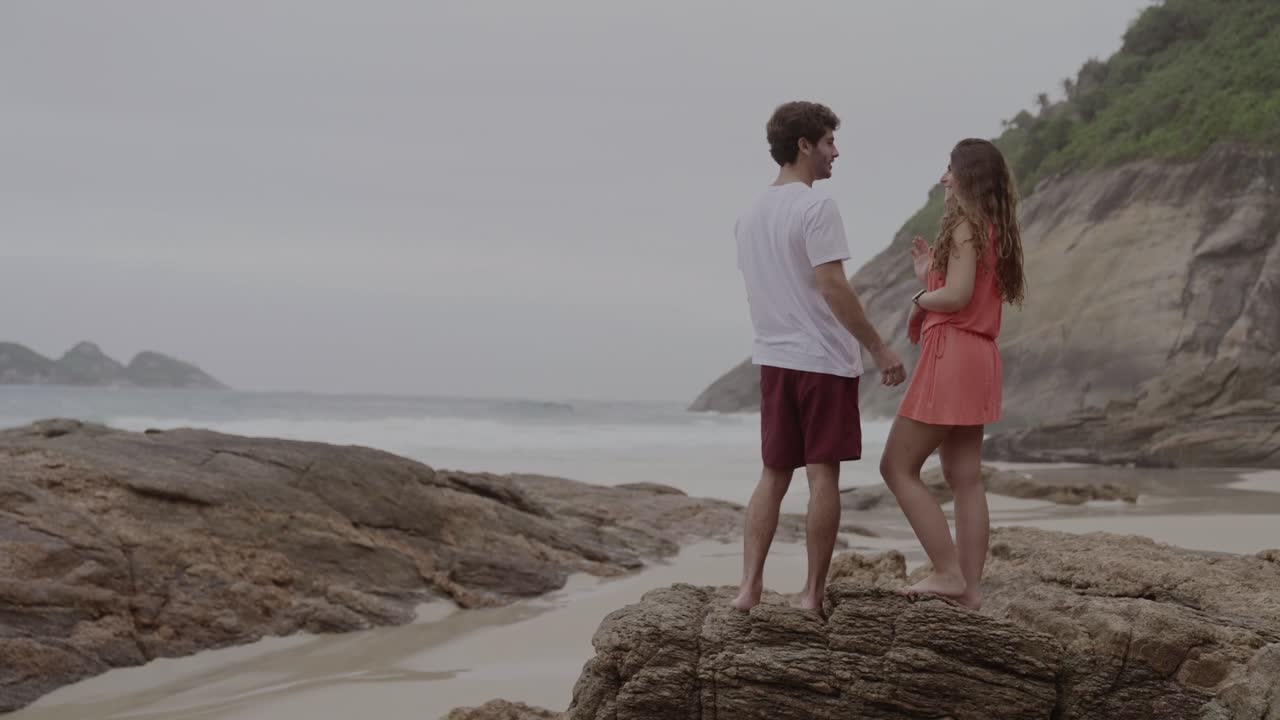 Couple standing on rocks at a scenic beach overlooking the ocean