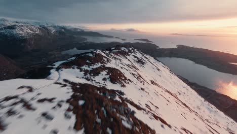 fast flying over snowy mountain ridge during colorful sunset in norway
