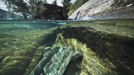 Mesmerizing-over-under-view-of-a-shallow-river-with-rocky-shores-and-clear-water