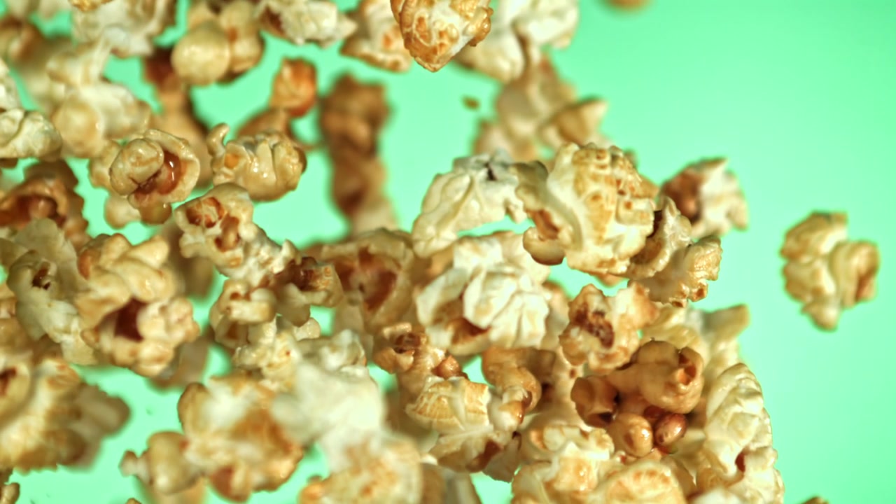 Caramel Popcorn Flying and Falling in Slow Motion on Green Background
