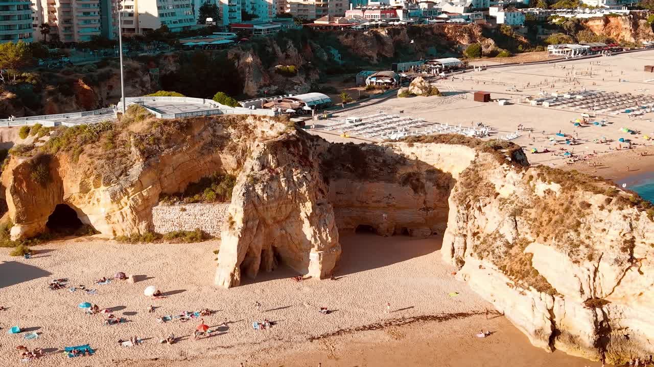 Visitatori si rilassano sulla spiaggia vicino alle scogliere in Portogallo durante una giornata estiva