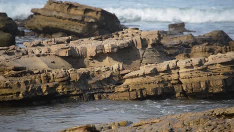 a beach view of a rock formation surrounded by water