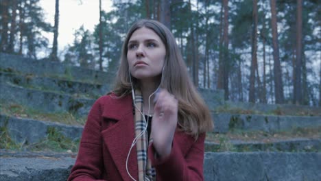 mujer escuchando música en un bosque de otoño