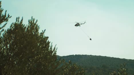 helicopter flying away after dropping water on forest fire