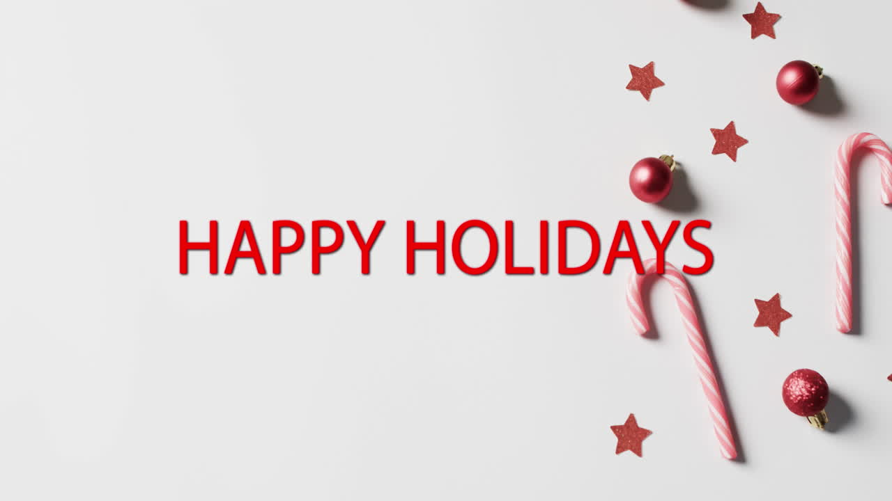 Happy holidays text in red with candy canes, red stars and christmas baubles on white background