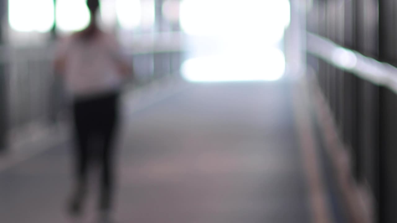 A person moves through a bright, blurred walkway, creating a sense of motion and light.