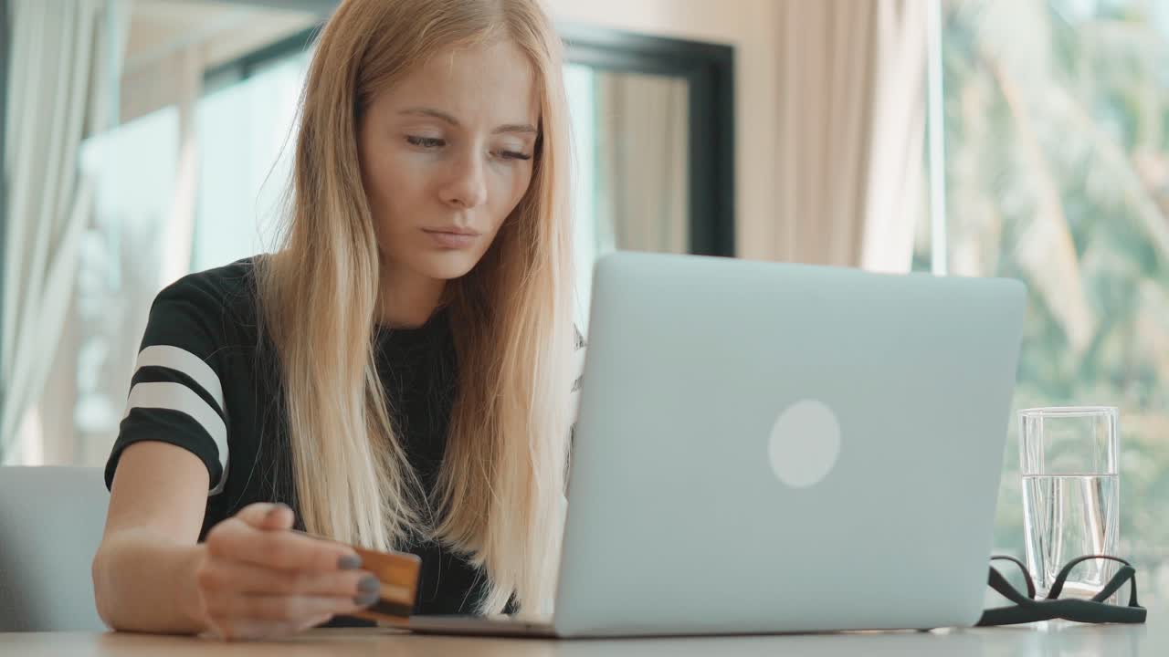 Ung kvinde foretager onlinebetaling med kreditkort og bærbar computer