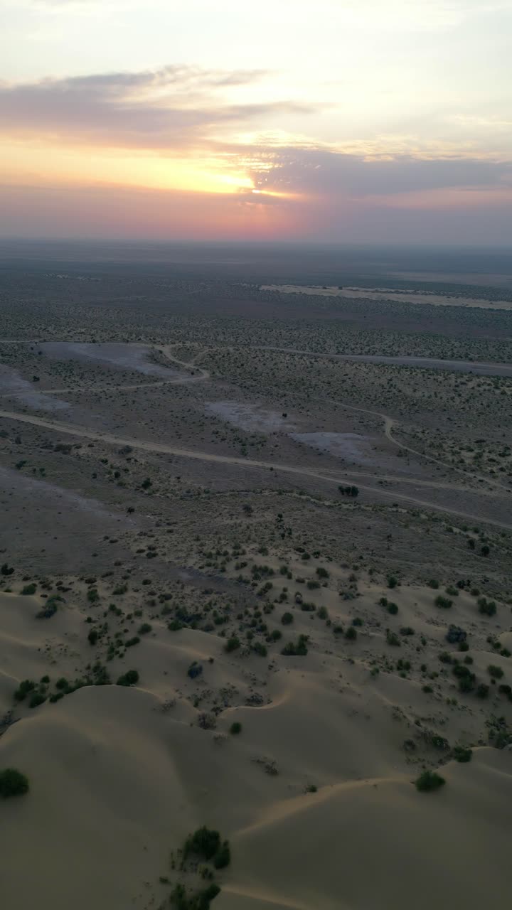 An aerial top view of golden sand dunes in Jaisalmer, Rajasthan, dotted with patches of green vegetation with the dramatic sky Rajasthan India 4K drone