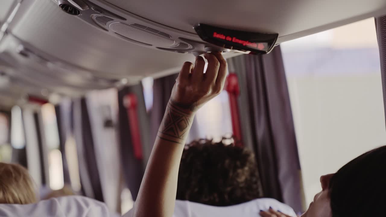 A person reaching for an overhead control inside a bus