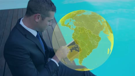 Animation-of-yellow-globe,-over-businessman-by-pool-using-tablet