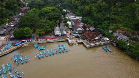 aerial footage of fishing port with many boat anchored on it with fish auction - baron beach, indonesia