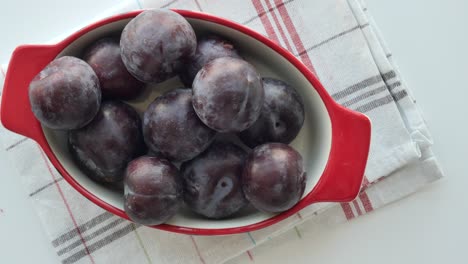 plums in a red bowl