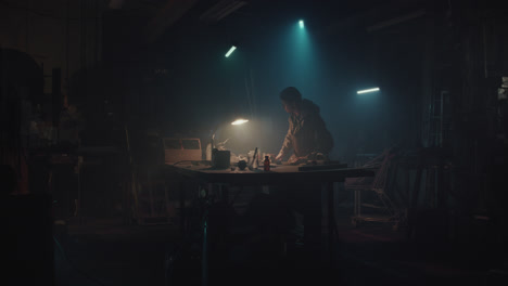 a bombmaker assembles a bomb in his workshop at night