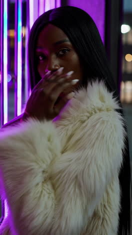 fashionable woman in faux fur coat with purple neon lights