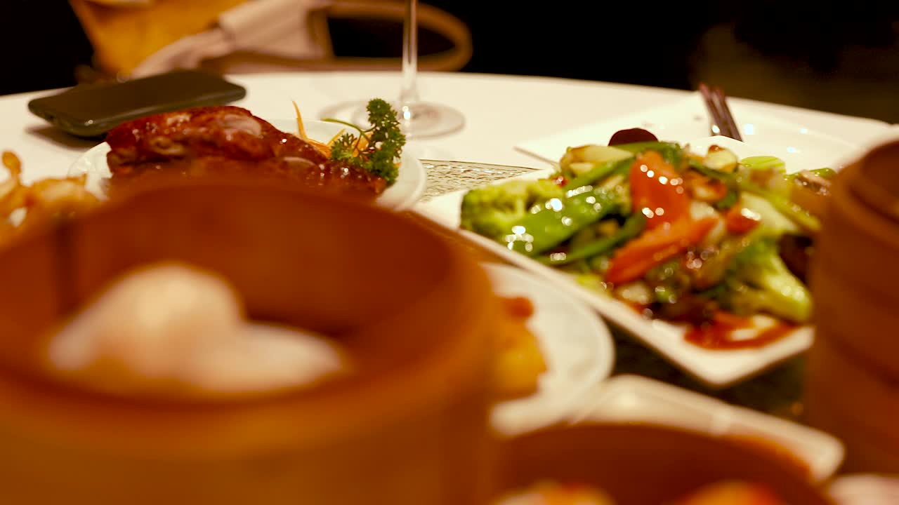 A vibrant array of dim sum dishes, including shrimp and vegetables, captured in warm lighting at a Chinese restaurant