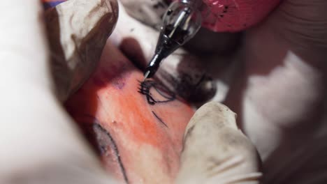 tattoo artist tattooing eyelashes around eye on skin, closeup shot of needle