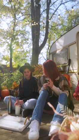 two friends enjoying autumn picnic by a campervan