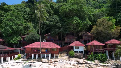 island hill huts in lush jungle fores, emerald waters lagoon