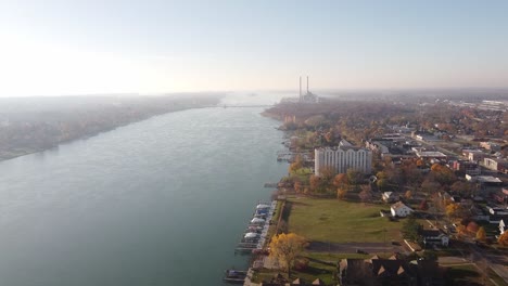 tranquil water of detroit river with structures on autumn landscape at trenton city in michigan, usa
