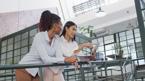 happy diverse female business colleagues using laptop discussing work at office
