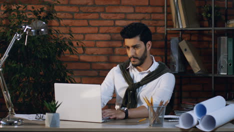 tired arabian businessman doing an exercise for a neck and resting while sitting in his office working with laptop