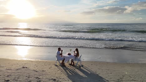 couple enjoys a romantic private dinner on the beach at sunset