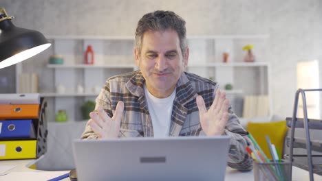 mature man working in home office gets excited and happy while using laptop.