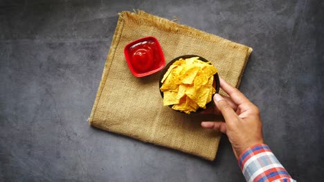la mano alcanzando para las papas fritas de tortilla con salsa