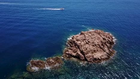 flying upwards, looking at an island and a boat behind, in the mediterranean sea