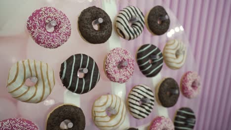 a vibrant assortment of donuts sits on a decorative stand, featuring various toppings and colors. the bakery event creates a festive and sweet ambiance for all attendees