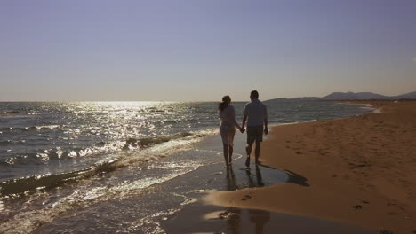 couple walking on beach at sunset