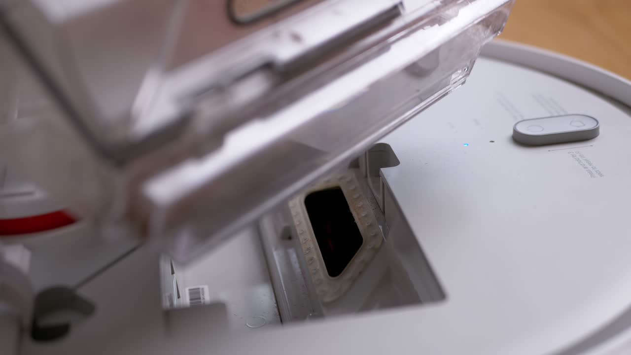 남자 손은 자동 로 진공청소기에서 먼지 컨테이너를 꺼니다.