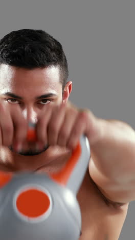 serious muscular man lifting kettlebell