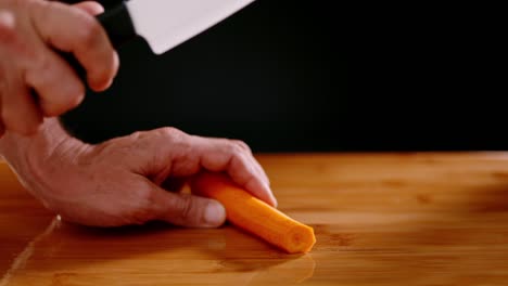 Cutting-orange-carrot-with-sharp-chef-knife,-slow-motion-view