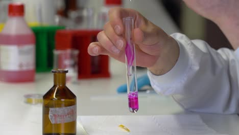 un químico mezcla productos químicos en un tubo de ensayo en el laboratorio