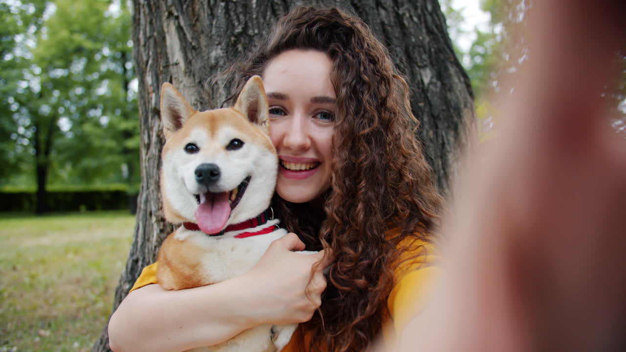 Mulher tirando uma selfie com seu cachorro Shiba Inu em um parque