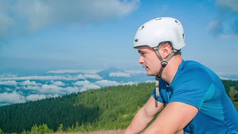 Man-with-helmet-on-bicycle-enjoys-beautiful-landscape-from-top-of-hill