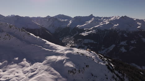 Drone aerial of Hotel Weisshorn, Switzerland. Iconic alpine hotel surrounded by snowy peaks and forests, offering breathtaking mountain scenery for travel, tourism and cinematic stock footage