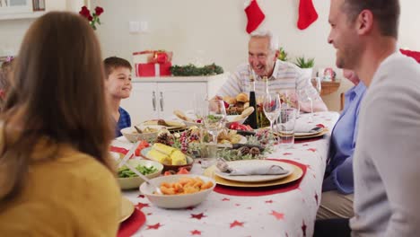 familia caucásica sentada en la mesa del comedor disfrutando del almuerzo juntos durante la navidad en casa