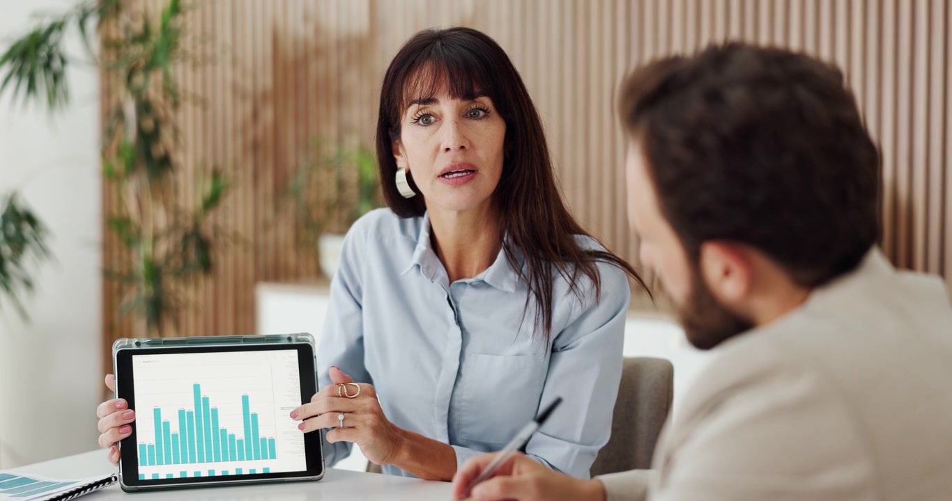 Empresaria presentando datos financieros en tableta a su colega
